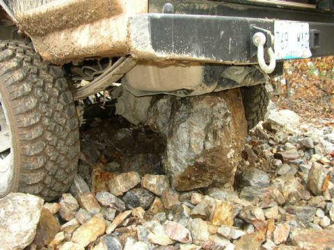 1995 Ford Bronco - Vehicle's rear tire and bumper are high-centered on large rocks, indicating off-road difficulty.