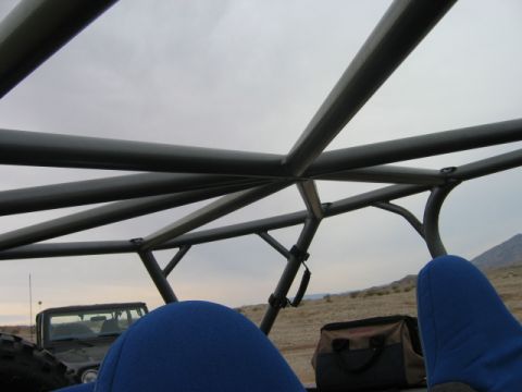 1985 Ford Bronco - View from inside a vehicle, focusing on the roll cage and seats, with another SUV in the distance.
