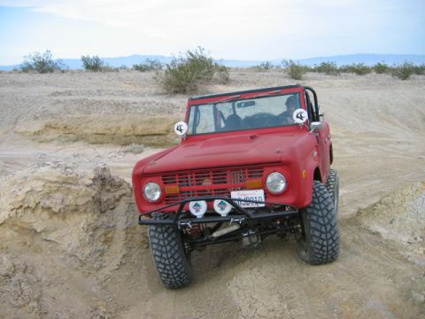 1985 Ford Bronco - Red Ford Bronco navigates a desert trail, its off-road capabilities.