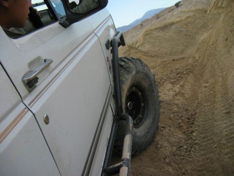 1985 Ford Bronco - This modified Ford Bronco is navigating a steep, sandy incline, its off-road capabilities.