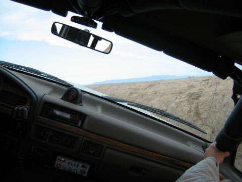 1985 Ford Bronco - View from inside a vehicle's cabin, showing the dashboard and a glimpse of the desert scenery through the windshield.