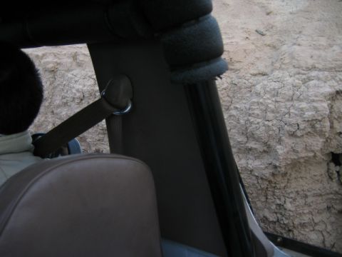 1985 Ford Bronco - Interior view of a vehicle with a seatbelt visible, against a backdrop of dry, cracked earth.