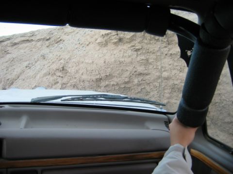 1985 Ford Bronco - The dashboard and windshield wipers are visible from the driver's perspective as the vehicle navigates a rough, rocky terrain.