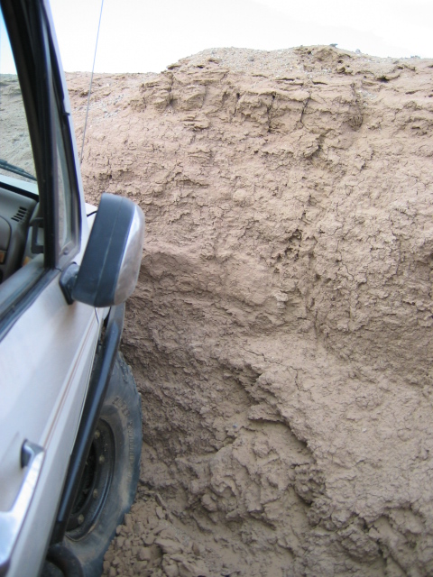 1985 Ford Bronco - A 1985 Ford Bronco navigates a narrow dirt path beside a steep, eroded cliff face.