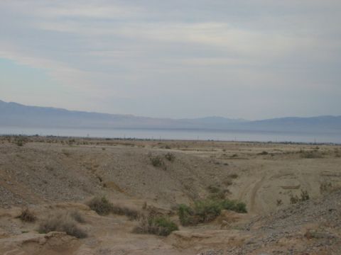 1985 Ford Bronco - A wide view of a desert scene with mountains and a hazy body of water under a cloudy sky.