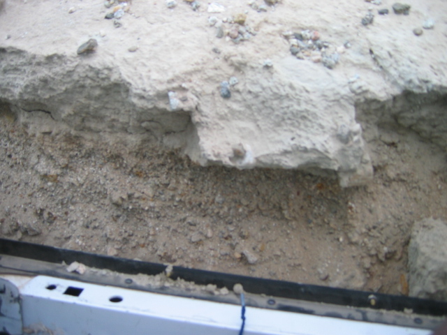 Broken concrete and gravel above a white panel with black trim