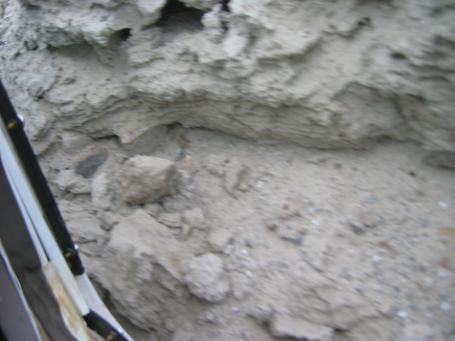 Close-up of gray dirt and small rocks with dark edge at left