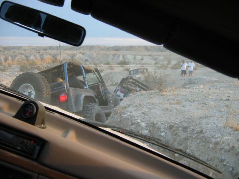 1985 Ford Bronco - Two off-road vehicles are seen navigating a challenging rocky terrain in a desert environment.