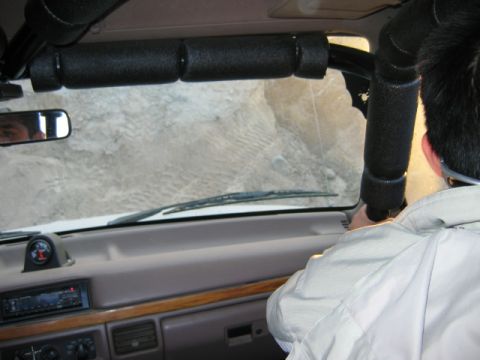 1985 Ford Bronco - Driving through sandy terrain from the interior of the vehicle. The dashboard and roll cage are visible.