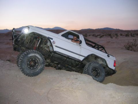 1985 Ford Bronco - Modified 1985 Ford Bronco navigates challenging terrain during a desert excursion at dusk.