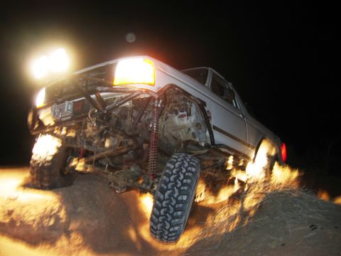 1985 Ford Bronco - This heavily modified Ford Bronco is shown off-roading at night, highlighting its suspension and tires.