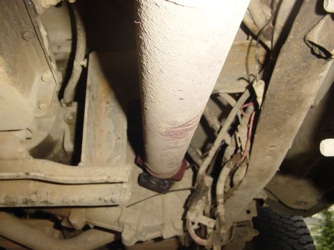 1987 Ford Bronco - The underside of a vehicle shows a driveshaft and transmission tunnel, with wiring harnesses visible.