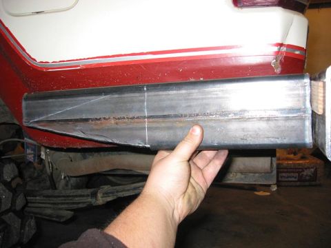 1985 Ford Bronco - A hand holds a metal tube against the rear of a vehicle, possibly for a custom bumper modification.