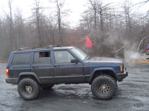 1993 Ford Bronco - A blue Jeep Cherokee XJ is seen from the side, with a red flag visible in the background.