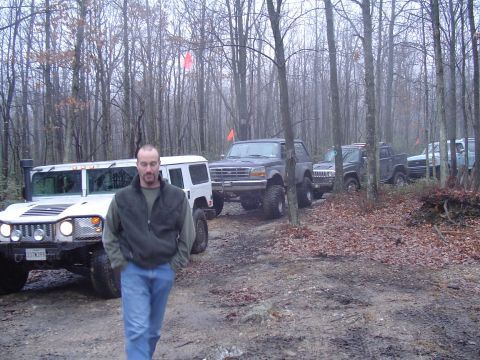 1993 Ford Bronco - A group of off-road vehicles are parked in a forest during an overcast day.