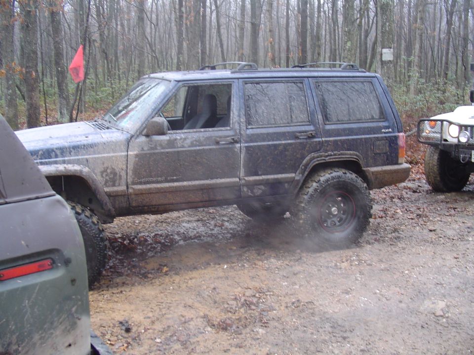 Muddy Jeep Cherokee XJ off-roading next to a white Hummer