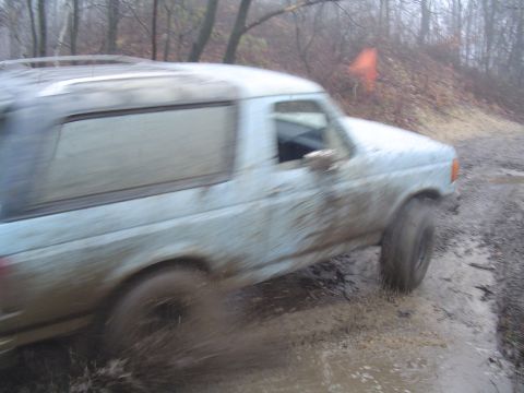 1993 Ford Bronco - This light blue Ford Bronco is navigating a challenging muddy off-road course.