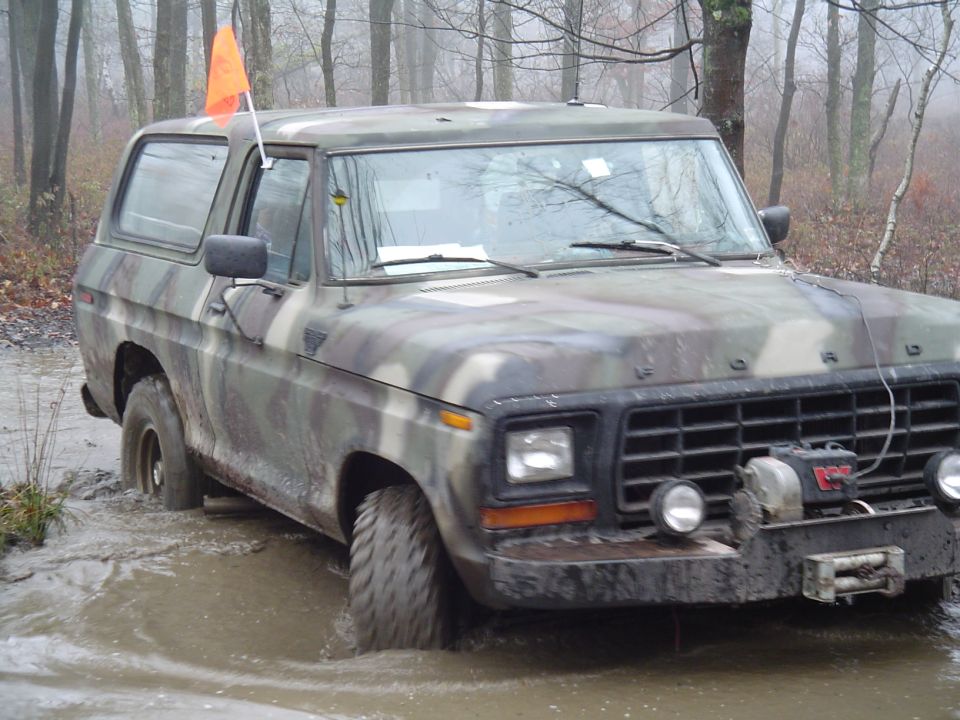 Camouflaged Ford Bronco stuck in mud, front view