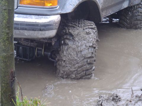 1993 Ford Bronco - This off-road vehicle navigates through muddy water, with another vehicle visible in the background.