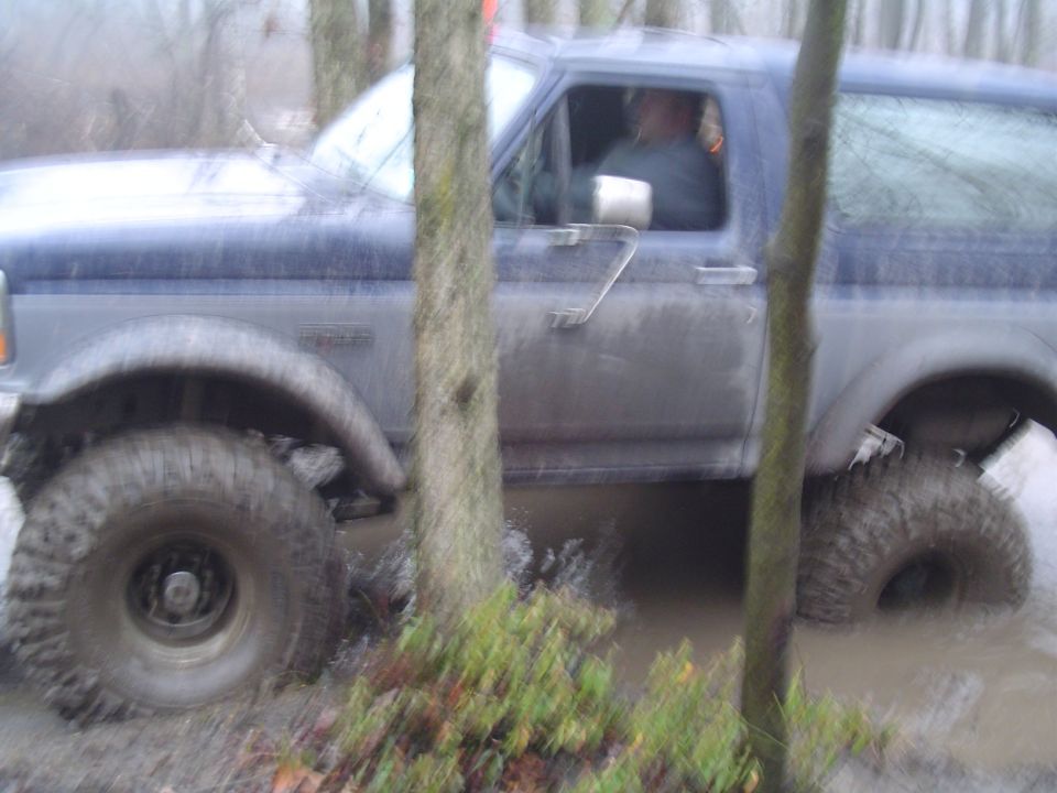 1993 Ford Bronco driving through mud and trees