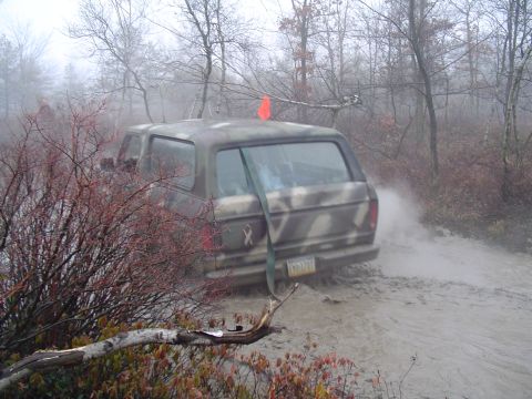 1993 Ford Bronco - SUV stuck in mud on a dirt road during a foggy day.