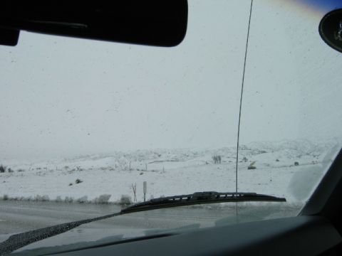 1985 Ford Bronco - View from inside a vehicle's cabin, looking out through the windshield at a snowy, mountainous terrain.