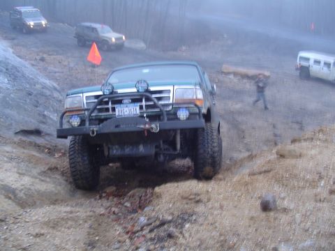 1993 Ford Bronco - 1993 Ford Bronco navigating a challenging off-road course with other vehicles present.