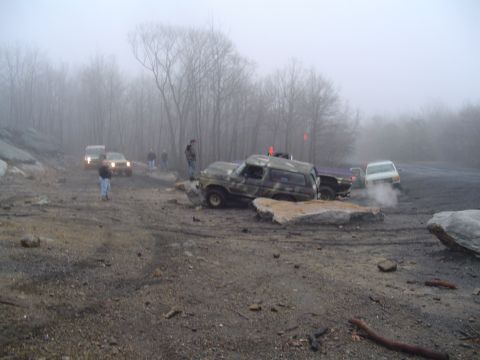 1993 Ford Bronco - Several vehicles navigate a rocky, off-road course on a foggy day.