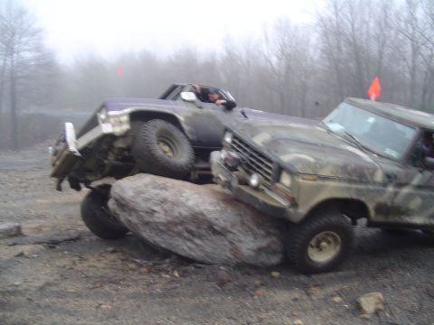 1993 Ford Bronco - Two trucks are shown navigating a difficult rocky obstacle course during an off-road event.
