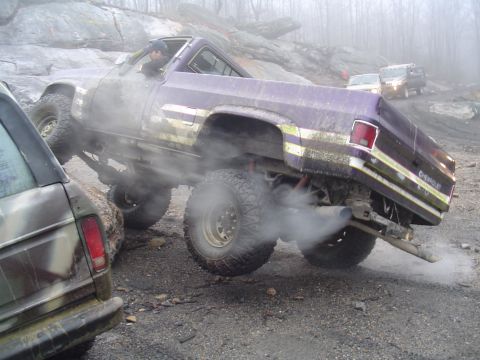 1993 Ford Bronco - Modified trucks navigate a rocky, foggy off-road course with large tires and visible exhaust.
