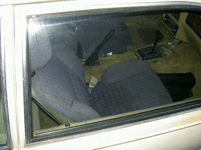 Interior of car seen through side window with gray cloth seats and floor shifter