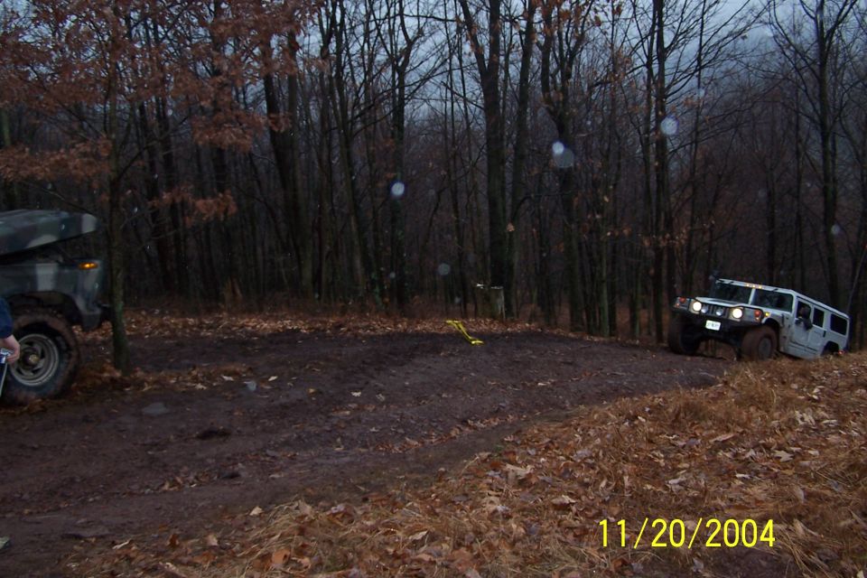 White Hummer H1 navigating a muddy off-road course with another vehicle partially visible