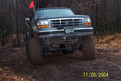 1979 Ford Bronco - A lifted Ford truck navigates a muddy, wooded path.