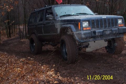 1979 Ford Bronco - This Jeep Cherokee XJ is navigating a muddy trail surrounded by trees and autumn foliage.