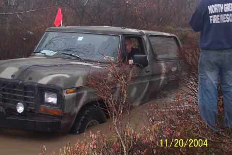 1979 Ford Bronco - Ford Bronco stuck in mud during an off-road event, with a person observing.