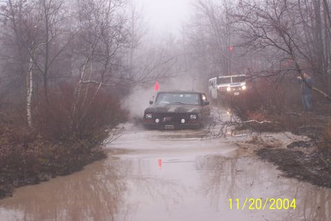 1979 Ford Bronco - Two off-road vehicles navigate a muddy trail on a foggy day.