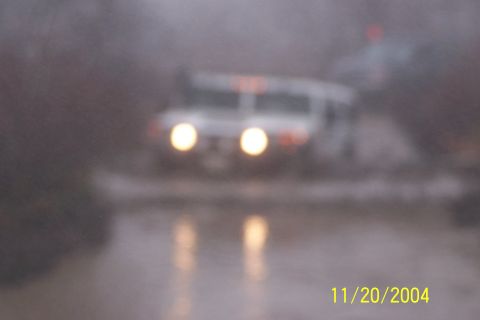 1979 Ford Bronco - A white SUV is seen driving through a body of water, with its headlights illuminated.