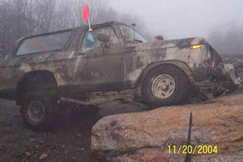 1979 Ford Bronco - Camouflaged Ford Bronco navigating rocky terrain with a red flag on its roof.