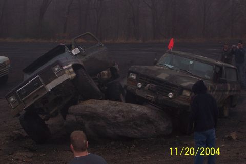 1979 Ford Bronco - Two off-road vehicles, including a 1979 Ford Bronco, tackle large rocks during an event.