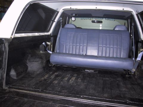 1993 Ford Bronco - The interior of an SUV shows a blue bench seat installed in the cargo area.