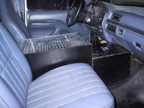 1993 Ford Bronco - The interior of a vehicle, blue-grey seats and a custom console with a clear, perforated top.