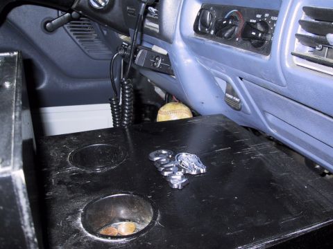 1993 Ford Bronco - The interior of a vehicle shows a baseball, coins in a cup holder, and several metal pieces on a black console.