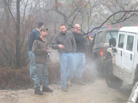 1995 Ford Bronco - Two off-road vehicles, a white Humvee and a dark green SUV, are visible in a misty, wooded environment with several people standing nearby.