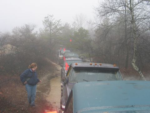 1995 Ford Bronco - Several vehicles are navigating a muddy trail in a foggy, wooded area.
