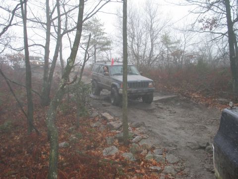 1995 Ford Bronco - A Jeep Cherokee XJ navigates a challenging off-road course on a foggy day.