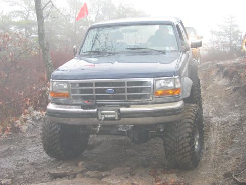 1995 Ford Bronco - Modified Ford F-Series truck navigating an off-road trail in foggy conditions.