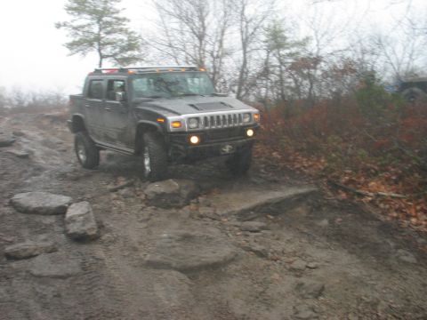 1995 Ford Bronco - A Hummer H2 SUT navigates a challenging off-road course with rocks and mud.