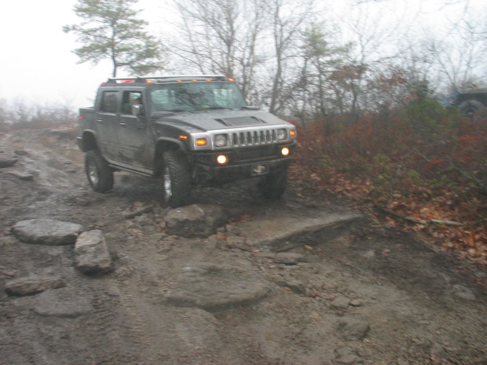 Dark Hummer H2 SUT off-roading on rocky, muddy terrain