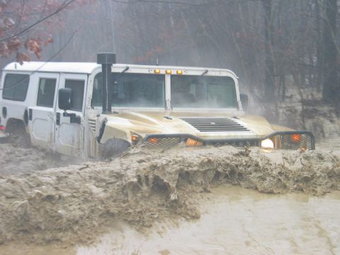 1995 Ford Bronco - A Humvee navigates through a thick mud pit during an off-road excursion.
