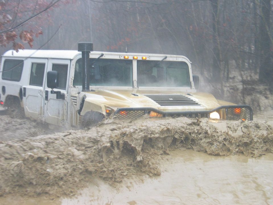 Humvee driving through deep mud, splashing water